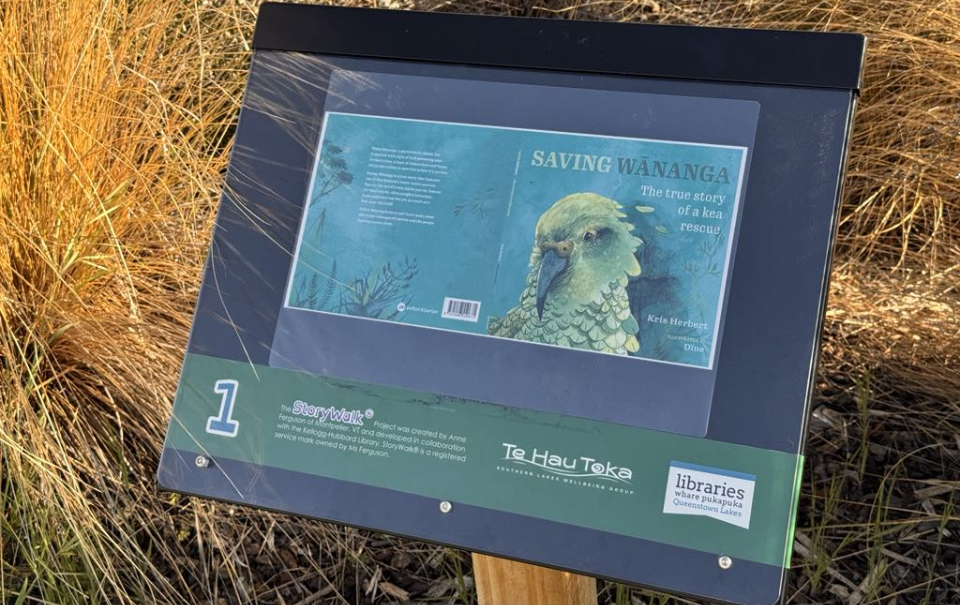 A wooden pillar with black board, an enlarged front cover of an illustrated children's book is displayed on the board covered by a clear Perspex sheet.